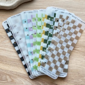 May include: A collection of planner inserts in a range of colours and patterns, including checkered and striped designs. The inserts feature text like "FIVE THO" and "HIGH PRIORITY". These inserts are designed for budgeting and planning.