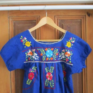 Vintage girls Mexican dress, various colored flowers on medium blue background, medium like new