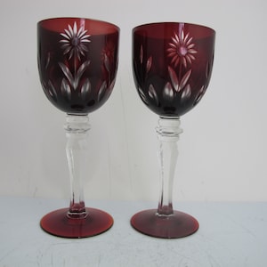 May include: Two red wine glasses with clear stems and bases. The glasses are etched with a floral design.