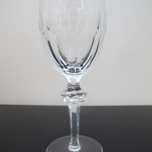 May include: A clear glass wine glass with a cut crystal design. The glass has a tall stem and a round base.