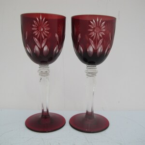 May include: Two red wine glasses with clear stems and bases. The glasses are etched with a floral design.