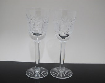 May include: Two clear glass wine glasses with a cut crystal design. The glasses have a tall, slender stem and a round base.