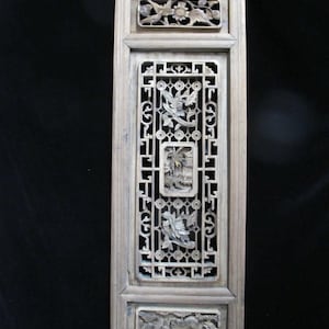 May include: A rectangular, light-colored wooden panel with intricate carvings. The panel features detailed relief carvings of birds, flowers, and architectural elements within a lattice design. The frame and carvings are in a neutral, aged tone.