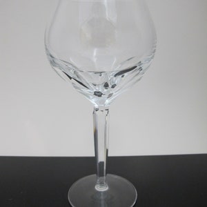 May include: A clear glass wine glass with a tall stem and a wide bowl. The bowl has a faceted design.