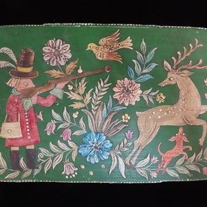 Puede incluir: Una bandeja ovalada de madera pintada a mano con fondo verde. La bandeja presenta a un cazador con un arma, un ciervo, un pájaro y varias flores.