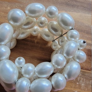May include: A white pearl bracelet with multiple strands of pearls. The bracelet is made of faux pearls and is a simple, elegant design.