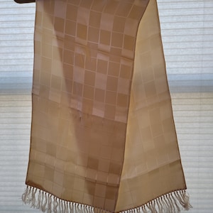 May include: A beige scarf with a checkered pattern and a fringe trim.