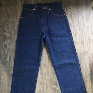 Puede incluir: Un par de pantalones vaqueros de mezclilla azul oscuro con un corte recto cl&aacute;sico.