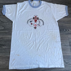 Könnte beinhalten: Weißes T-Shirt mit blauem Ringel. Das Shirt zeigt ein Vintage-Logo des 75. Jahrestages der Boy Scouts of America mit dem Text "Kia Kima Scouting's Anniversary 75 Years".