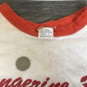 May include: White and orange baseball style t-shirt with the text "Tangerine Bowl" in red script. The tag reads "100% Cotton Size L."