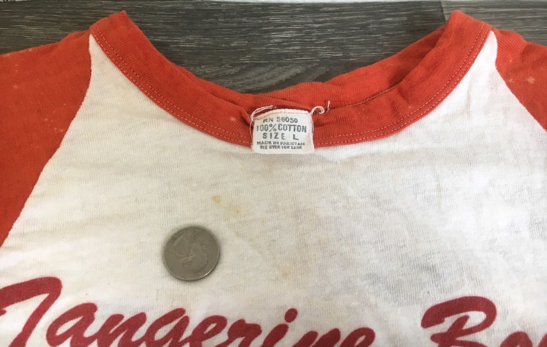 May include: White and orange baseball style t-shirt with the text "Tangerine Bowl" in red script. The tag reads "100% Cotton Size L."