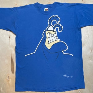 May include: A blue t-shirt with a cartoon image of The Tick, a blue superhero with a large grin and antennas.