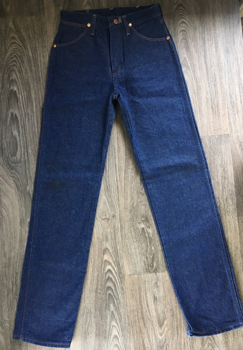 Puede incluir: Un par de pantalones vaqueros de mezclilla azul oscuro con un corte recto cl&aacute;sico.