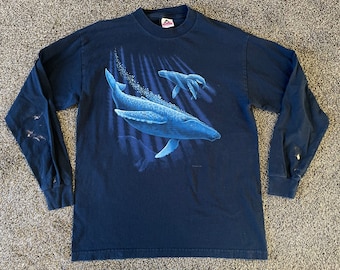 May include: A dark blue long-sleeved t-shirt with a graphic print of a whale and a baby whale swimming in the ocean. The graphic is in shades of blue and white.