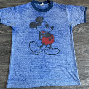 May include: A blue and navy blue t-shirt with a vintage Mickey Mouse graphic. The shirt is made of a soft, lightweight fabric.