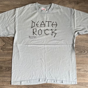 May include: A light gray t-shirt with the words "DEATH ROCK" printed in black in a stylized font.