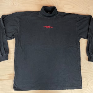 May include: Black long-sleeve mock neck shirt with a red embroidered eye design.