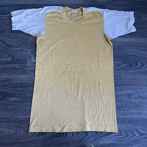 May include: A yellow t-shirt with white sleeves. The shirt is made of a soft, lightweight fabric.