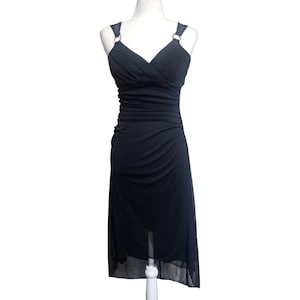 May include: A black dress with a V-neckline and spaghetti straps. The dress features a ruched bodice and a flowing, asymmetrical skirt. The straps are attached to the dress with silver rings. The dress is displayed on a white mannequin.