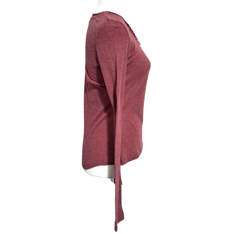 May include: A long-sleeved, maroon-colored shirt with a V-neck and a decorative trim along the neckline. The shirt is made of a soft, lightweight material and has a slim fit. The sleeves are long and end in a simple cuff.
