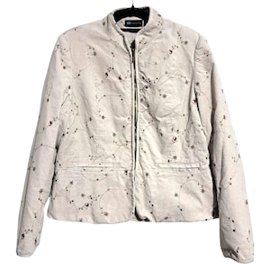 May include: Beige corduroy jacket with a floral embroidery design. The jacket has a full-length zipper, two front pockets, and a round collar. The floral embroidery features small flowers and stems in shades of brown and burgundy.