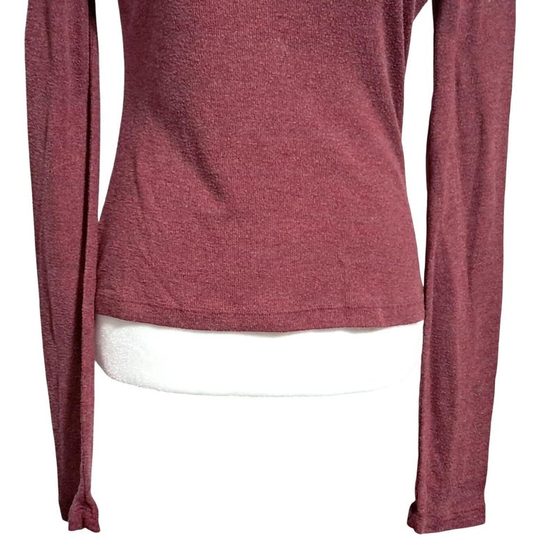May include: A long-sleeved, burgundy-colored shirt. The shirt has a ribbed texture and a fitted silhouette. The sleeves are long and end with a slight flare at the wrists. The fabric appears to have a subtle sheen.