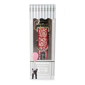 May include: A red and white patterned dog collar with a silver D-ring, packaged in a white box with a striped pattern. The box features the text "You Had Me at Woof" and "Artist-Made Dog Collar & Leash".