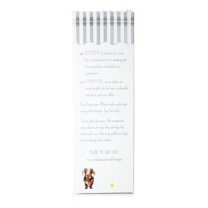May include: A white rectangular product box with a striped top design and text. The box features a dachshund illustration and text that reads "MADE IN THE USA". The box is for a dog product.