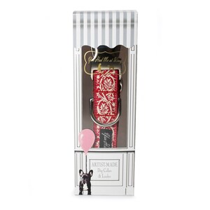 May include: A red and white patterned dog collar and leash set displayed in a decorative box. The collar features a floral design. The box has a striped top and a graphic of a dog holding a balloon. Text on the box reads "Artist-Made Dog Collar & Leash."