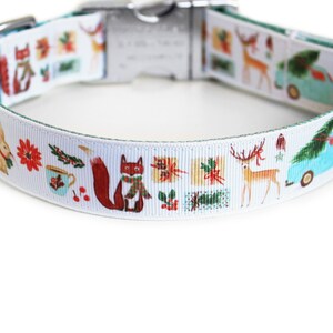 May include: White dog collar with a festive holiday design. The collar features illustrations of a fox, deer, gifts, and a blue truck carrying a Christmas tree. The collar has a teal backing and a silver metal clasp.