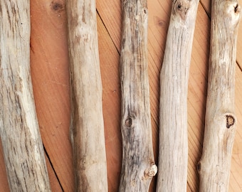 May include: Five pieces of driftwood, varying in length and thickness, with a natural, weathered brown color. The driftwood is arranged on a wooden surface.