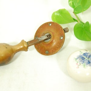 May include: Antique brass door knob with a wooden handle and a porcelain knob with a blue floral design.