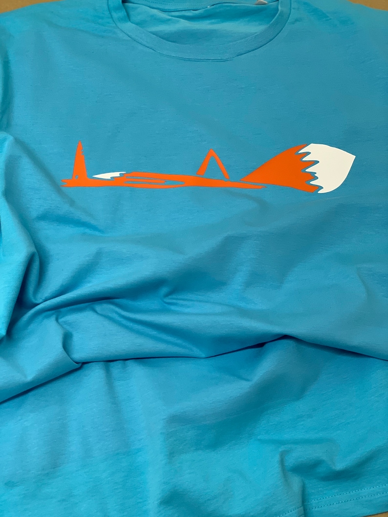 K&ouml;nnte beinhalten: Ein hellblaues T-Shirt mit einem stilisierten orangefarbenen Fuchsdesign. Der Fuchs schaut nach links und hat eine wei&szlig;e Schwanzspitze.
