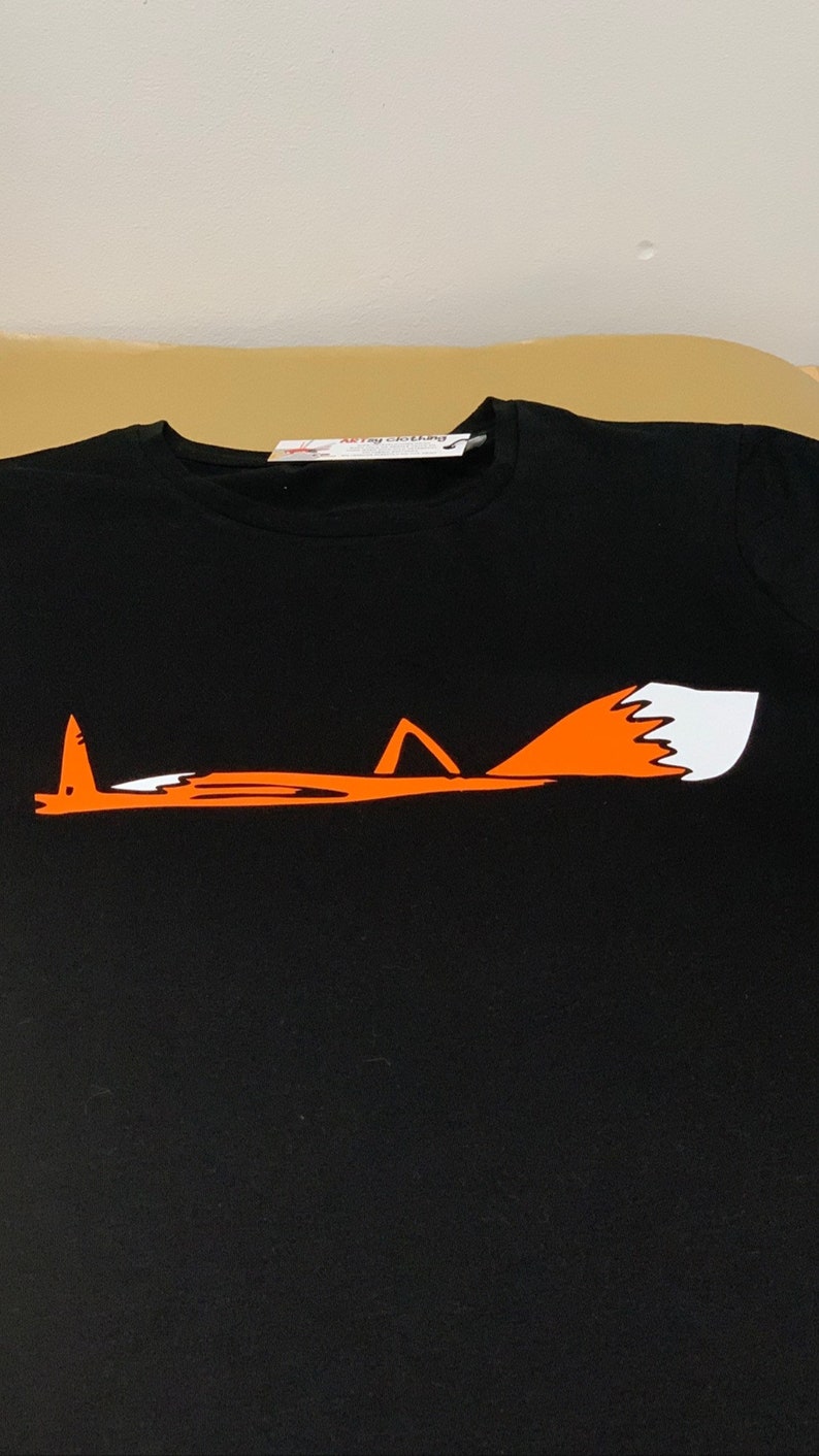 K&ouml;nnte beinhalten: Schwarzes T-Shirt mit einem orangefarbenen Fuchs-Motiv. Der Fuchs liegt mit eingerolltem Schwanz. Die Spitze des Fuchsschwanzes ist wei&szlig;.