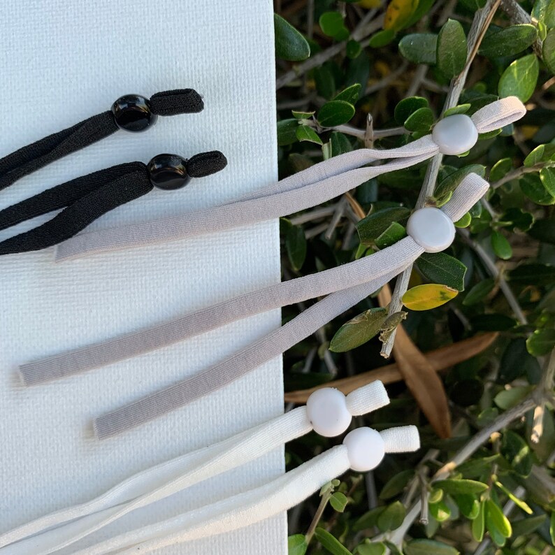 May include: Three sets of elastic cord with adjustable toggles. One set is black, one is gray, and one is white.