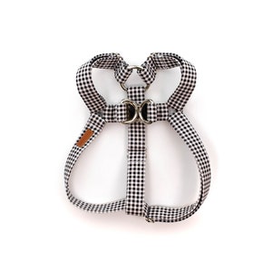 May include: Black and white checkered dog harness with a silver buckle.