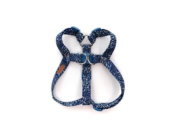 May include: A blue and white patterned dog harness with blue plastic buckles and silver metal rings.