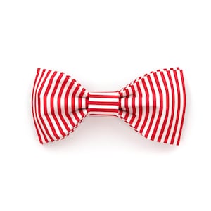 May include: A red and white striped bow tie. The bow tie is made of fabric and has a classic shape.