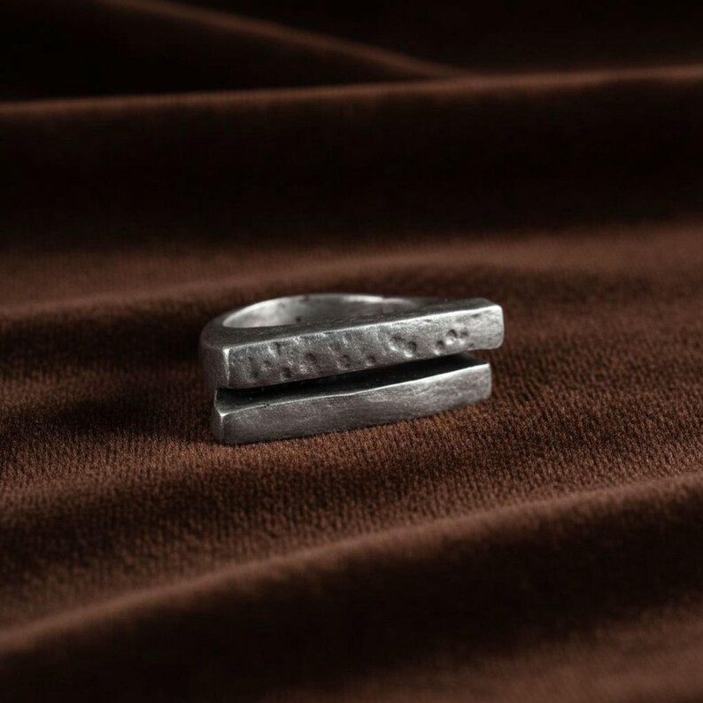 Geometric silver bar ring with a hand-hammered texture, photographed on soft brown fabric. The split-band design gives it a raw, modern edge. Minimalist and gender-neutral piece for everyday wear or gifting. Rannka handcrafted jewelry.