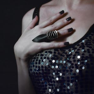 Bold Ring Silver Oxidized Chunky Ring on a women's hand paired with edgy pointy black leather ring. the woman is wearing silver dress with sequence and it appears to be at the party