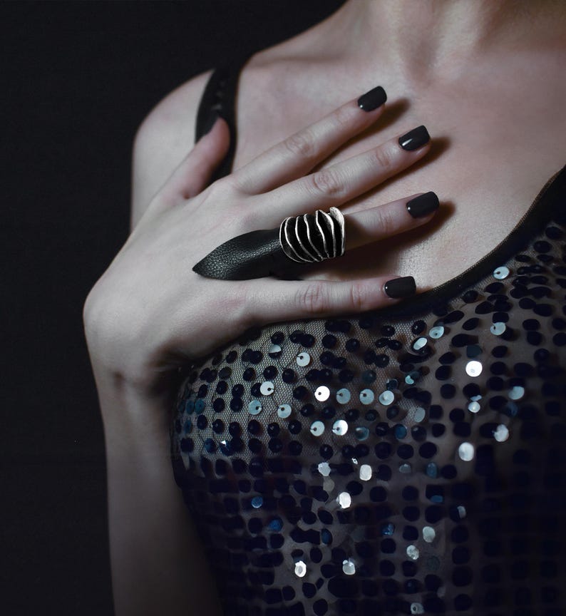 Bold Ring Silver Oxidized Chunky Ring on a women's hand paired with edgy pointy black leather ring. the woman is wearing silver dress with sequence and it appears to be at the party