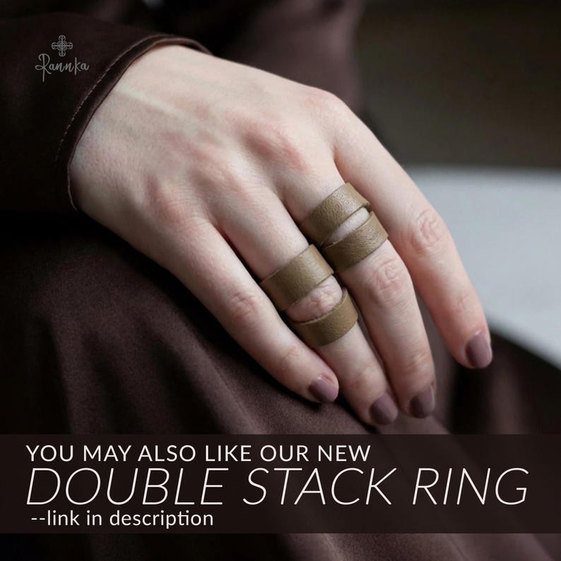 May include: Two stacked, light brown leather rings are worn on a hand with manicured nails. The rings have a unique design with cut-out sections. Text on the image reads "YOU MAY ALSO LIKE OUR NEW DOUBLE STACK RING --link in description."