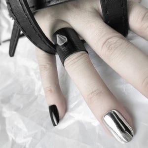 This Spike Leather Ring is a black vegan leather finger cuff with a silver metal stud, perfect for fans of punk jewelry and alternative fashion