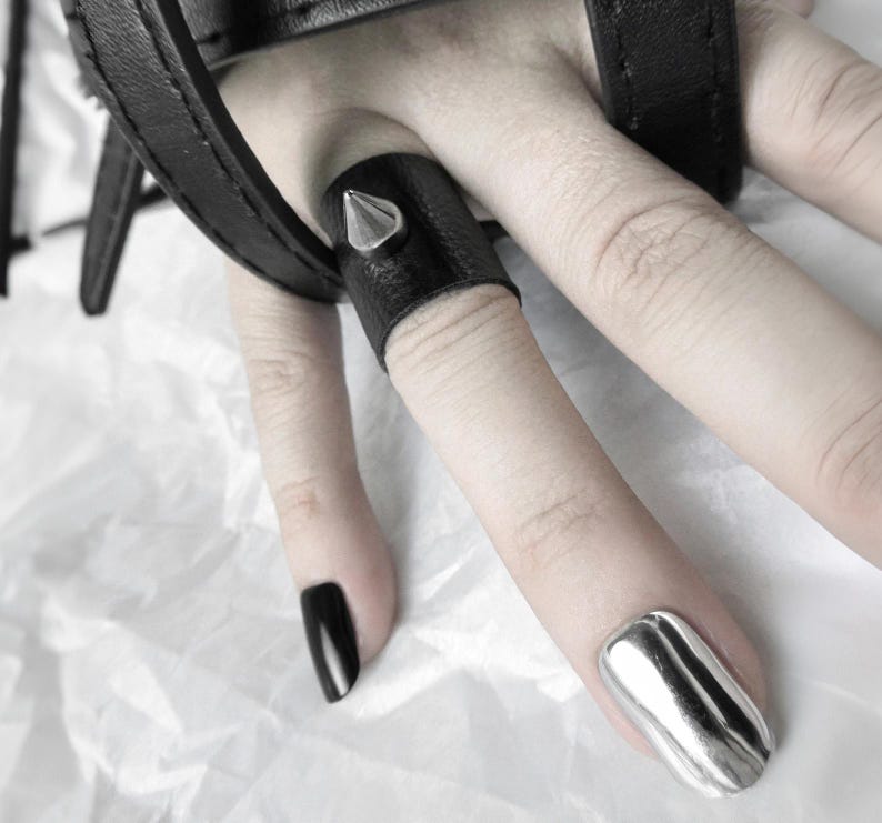 This Spike Leather Ring is a black vegan leather finger cuff with a silver metal stud, perfect for fans of punk jewelry and alternative fashion