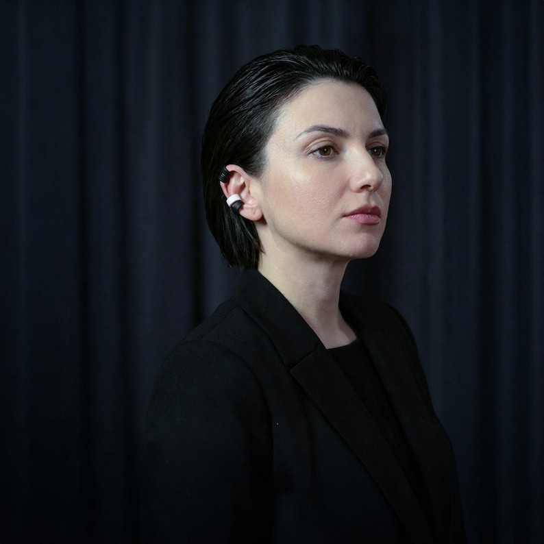 Black and white ear cuff set worn without ear piercings, stacked ear jewelry hugging the ear rim, modern no hole earrings styled on model in dark studio setting, minimalist ear accessories with matte finish, contemporary sculptural ear jewelry by Rannka.
