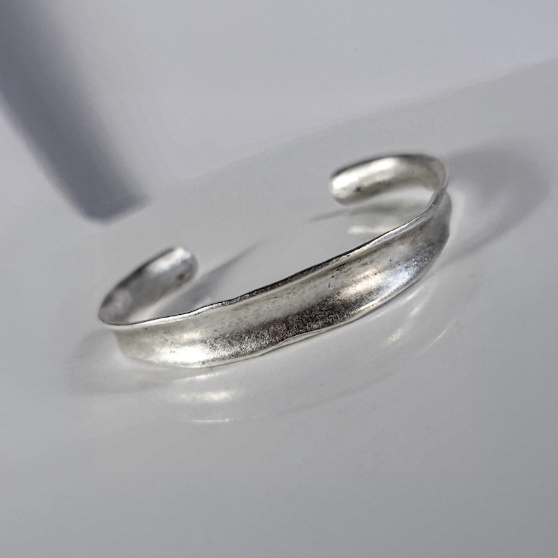 Rannka matte silver bracelet cuff for women with a thin open design and subtle brutalist shape on a white gray background with soft shadows