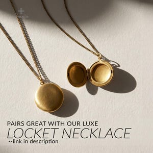 May include: Two gold-colored locket necklaces on a white surface. One locket is closed, the other is open, revealing the interior. The necklaces are round with a simple design. Text at the bottom reads "PAIRS GREAT WITH OUR LUXE LOCKET NECKLACE".