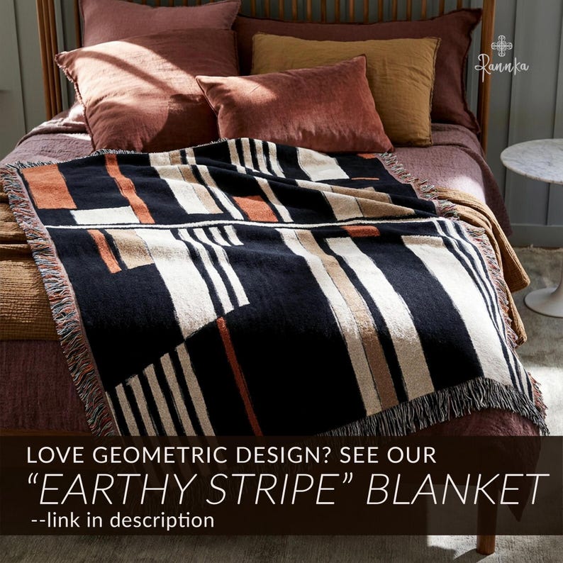 May include: A black blanket with a geometric design of white, tan, and orange stripes. The blanket has a fringed edge and is displayed on a bed with pillows. The text on the image reads "EARTHY STRIPE" BLANKET.