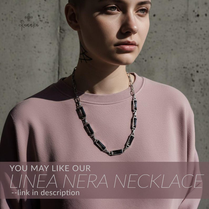 Peut inclure: Un collier argent&eacute; orn&eacute; de pierres noires rectangulaires. Le collier est port&eacute; par une personne v&ecirc;tue d'un sweat-shirt rose. Le texte "YOU MAY LIKE OUR LINEA NERA NECKLACE --link in description" est visible.