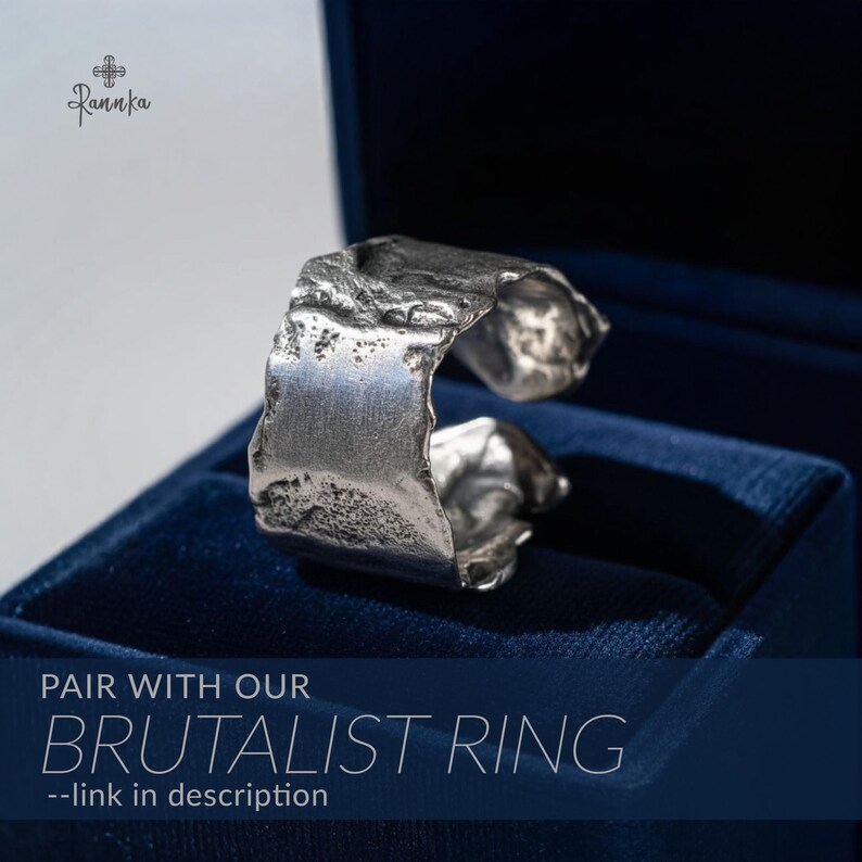 May include: A silver-colored Brutalist ring with a textured, uneven surface. The ring is displayed in a dark blue velvet jewelry box. The text "PAIR WITH OUR BRUTALIST RING --link in description" is visible at the bottom of the image.